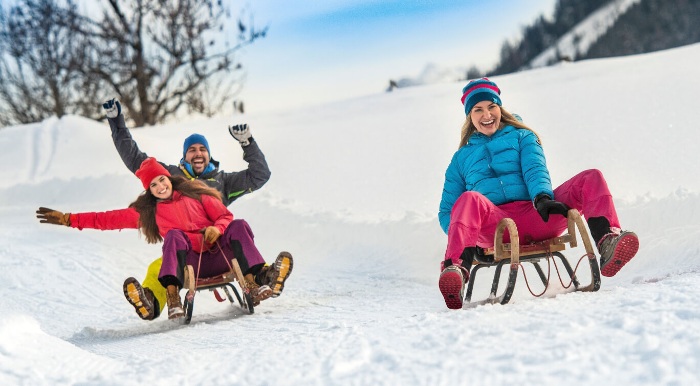 Spaß beim Schlitten fahren im Winterurlaub mit Freunden im Salzburger Land, Flachau